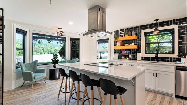 A modern kitchen with a large island, bar stools, a built-in stove, and a view of the outdoors. - Tranquille Resort (Hiawassee)
