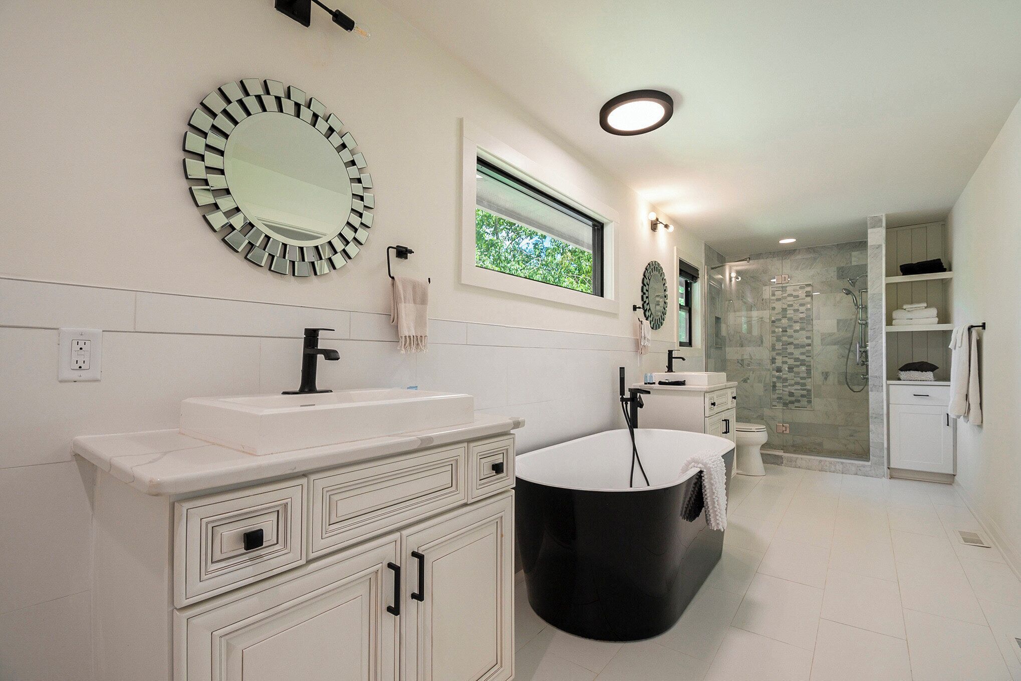 A modern bathroom with a large mirror, a bathtub, and a shower area.