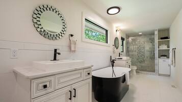 A modern bathroom with a large mirror, a bathtub, and a shower area.