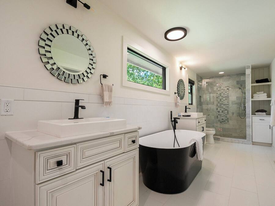 A modern bathroom with a large mirror, a bathtub, and a shower area.