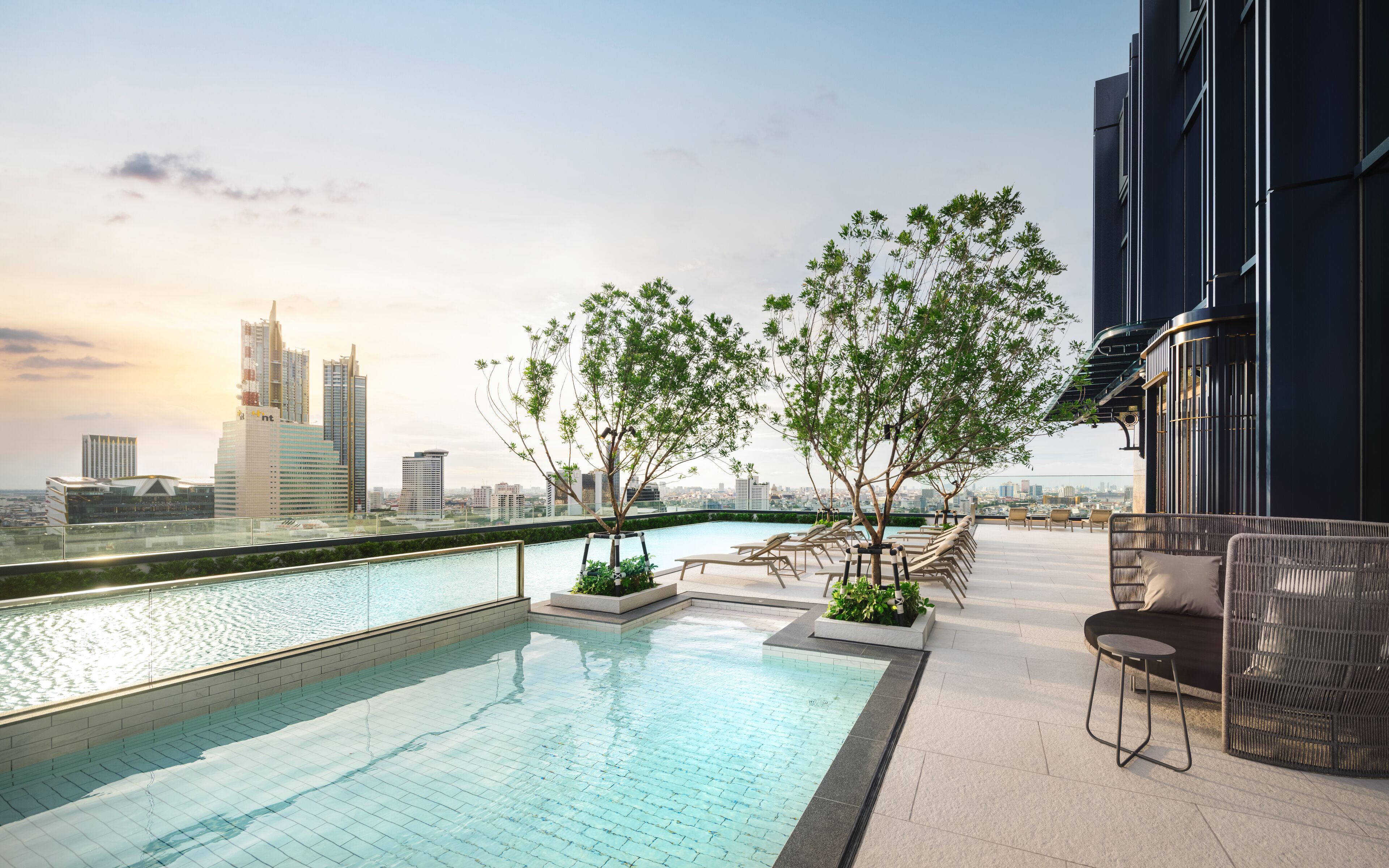 Piscina no terraço com espreguiçadeiras e vista para a cidade.