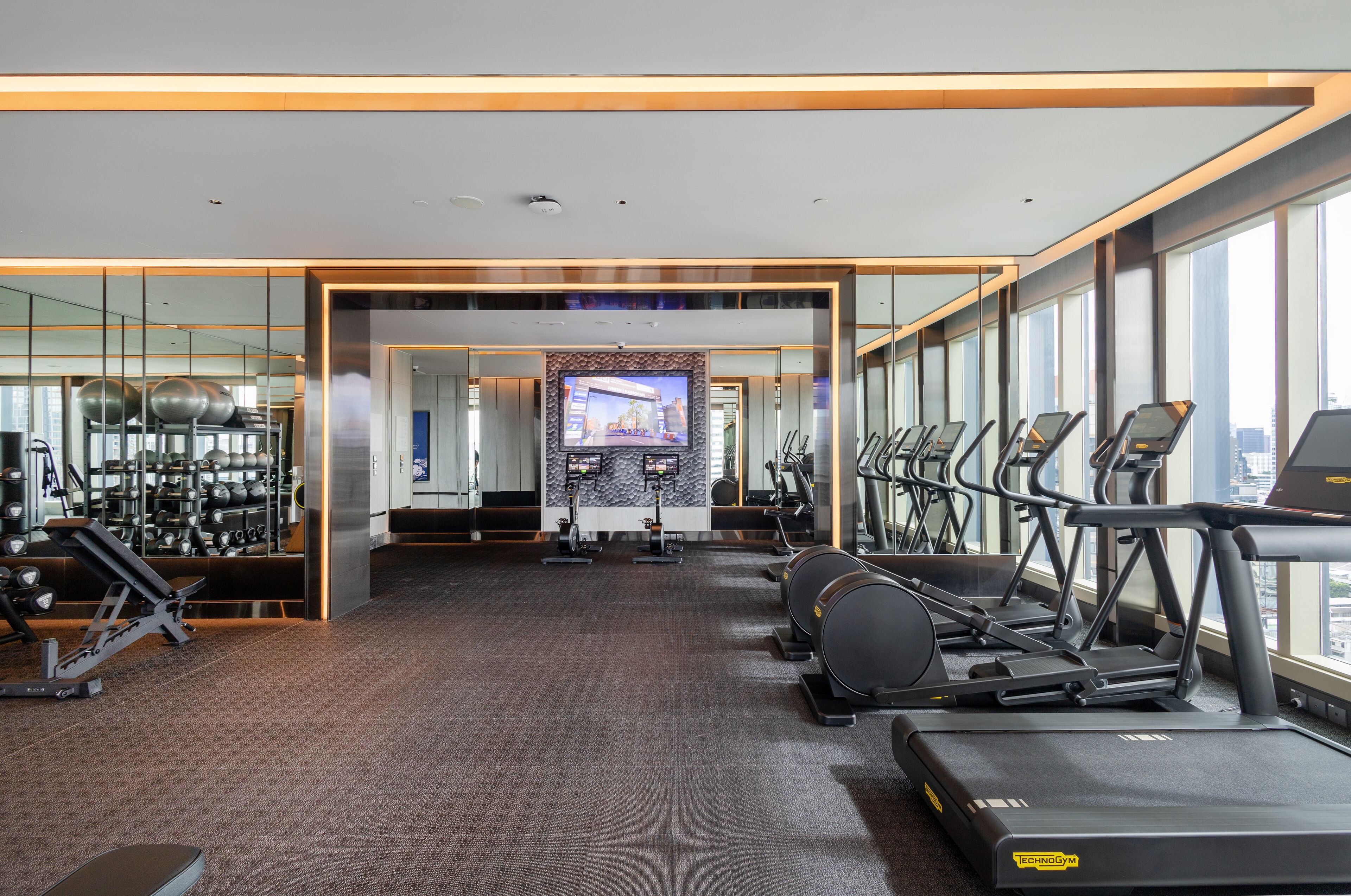 A modern gym with treadmills, exercise bikes, and weight machines.