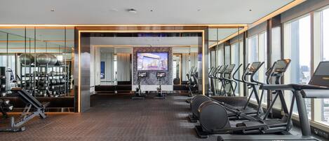 A modern gym with treadmills, exercise bikes, and weight machines.