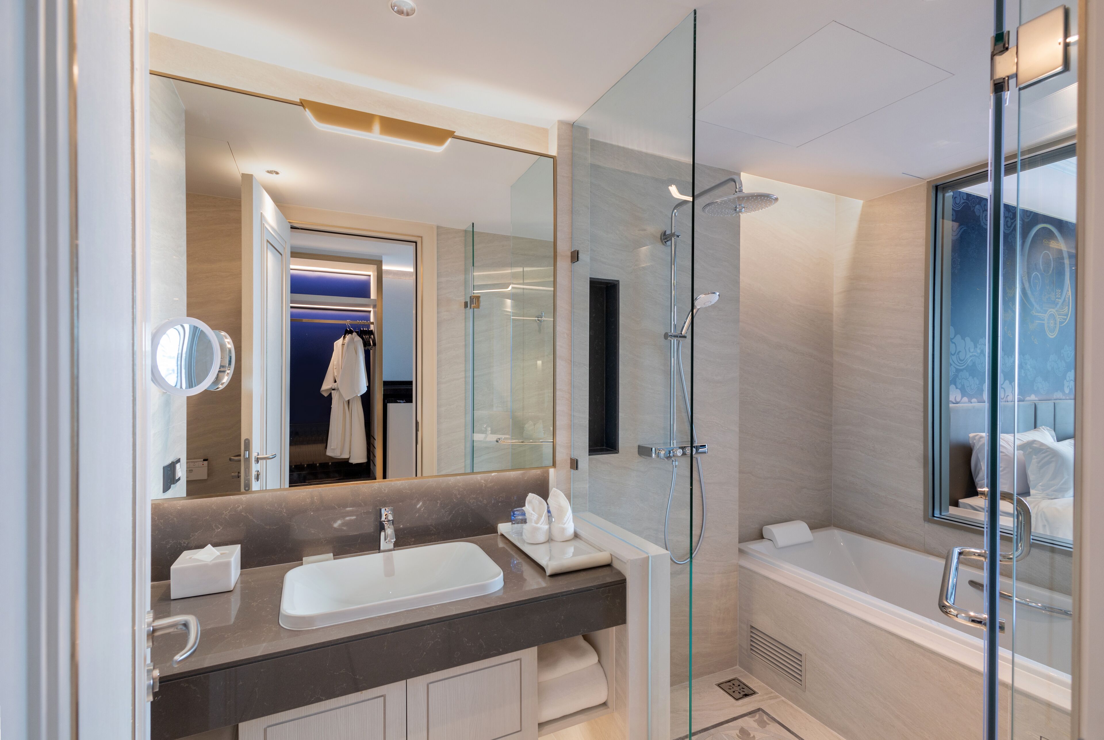 Une salle de bain moderne avec une douche à parois de verre, un grand miroir, un lavabo et une baignoire.