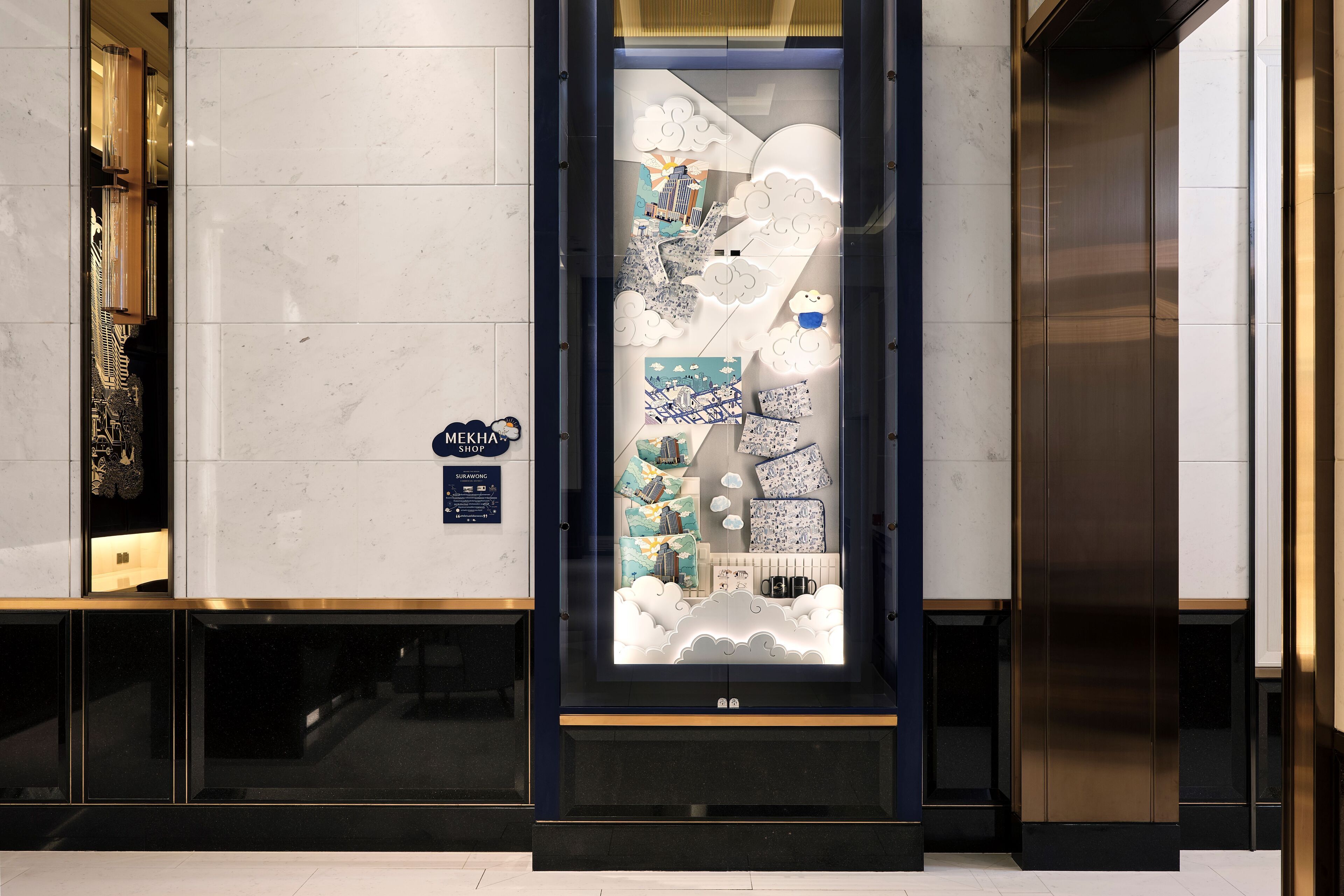 A modern hotel lobby with a glass display case containing various items.
