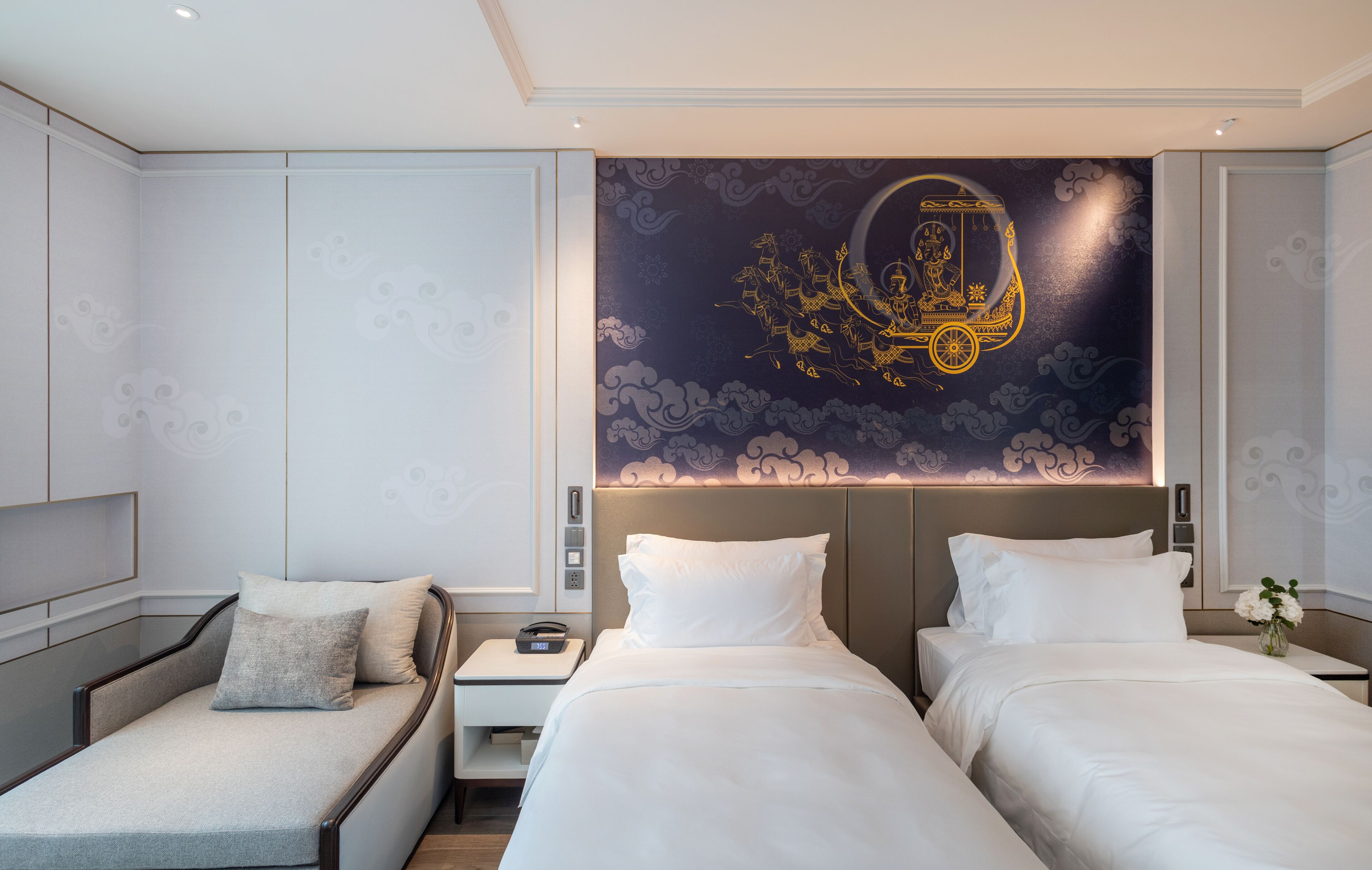 A modern hotel room with two beds, a sofa, and a decorative wall mural.