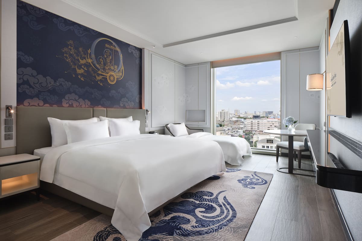 A modern hotel room with a large bed, a desk, and a city view.