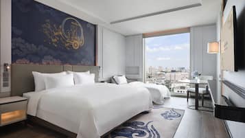Ein modernes Hotelzimmer mit einem großen Bett, einem Schreibtisch und Blick auf die Stadt.