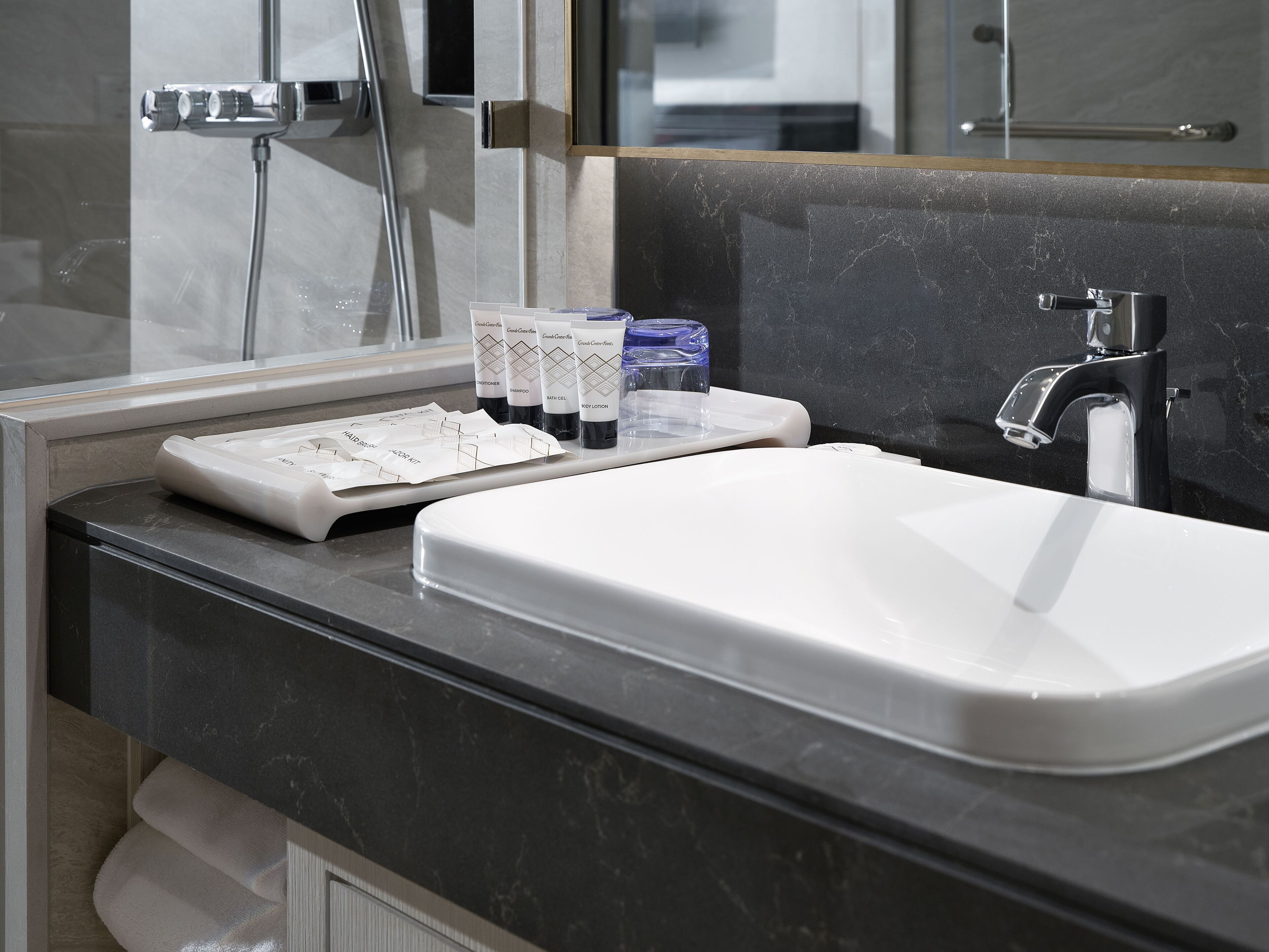 A bathroom with a white sink, a mirror, and toiletries on the counter.