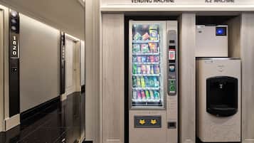 A vending machine and an ice machine in a hallway with a modern design.