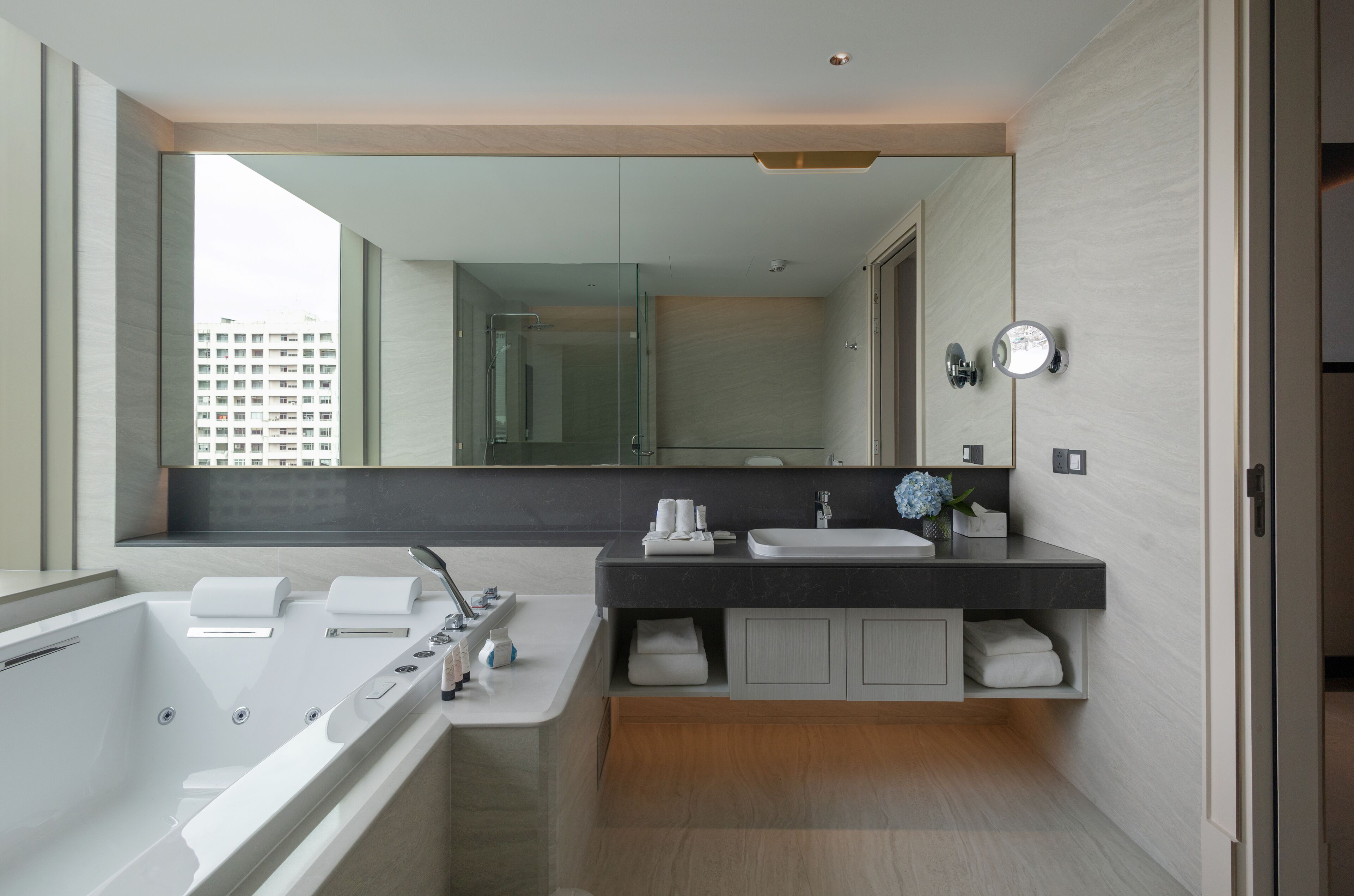 A modern bathroom with a large mirror, a bathtub, a sink, and a vanity.