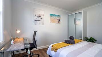 Una camera da letto con un letto, una scrivania, una sedia e due quadri appesi al muro.