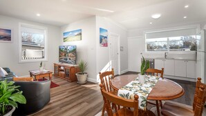 A modern living room with a dining area, wooden furniture, and potted plants.