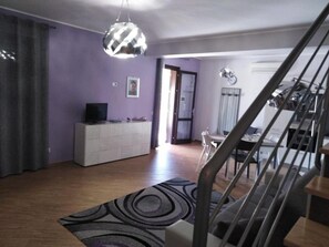 A living room with a sofa, a TV, a white cabinet, and a patterned rug. - 2 Bedroom Villa in Castellammare del Golfo (Castellammare del Golfo)
