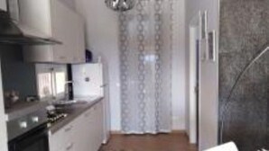 A modern kitchen with white cabinets, a built-in oven, and a stainless steel range hood.