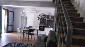 A modern living room with a sofa, a dining table, and a staircase.