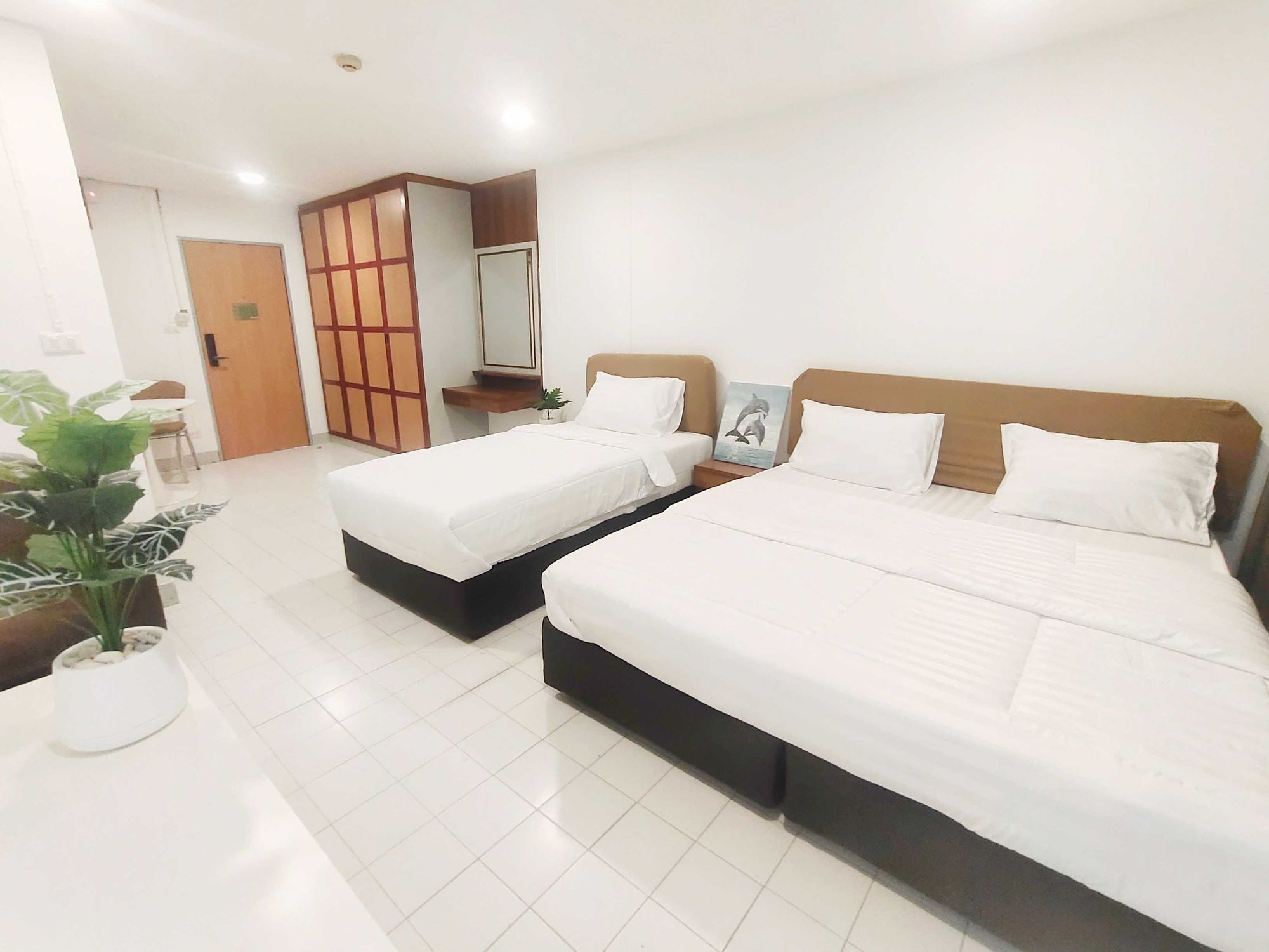 A hotel room with two beds, a small table with a plant, and a sliding door leading to a bathroom.