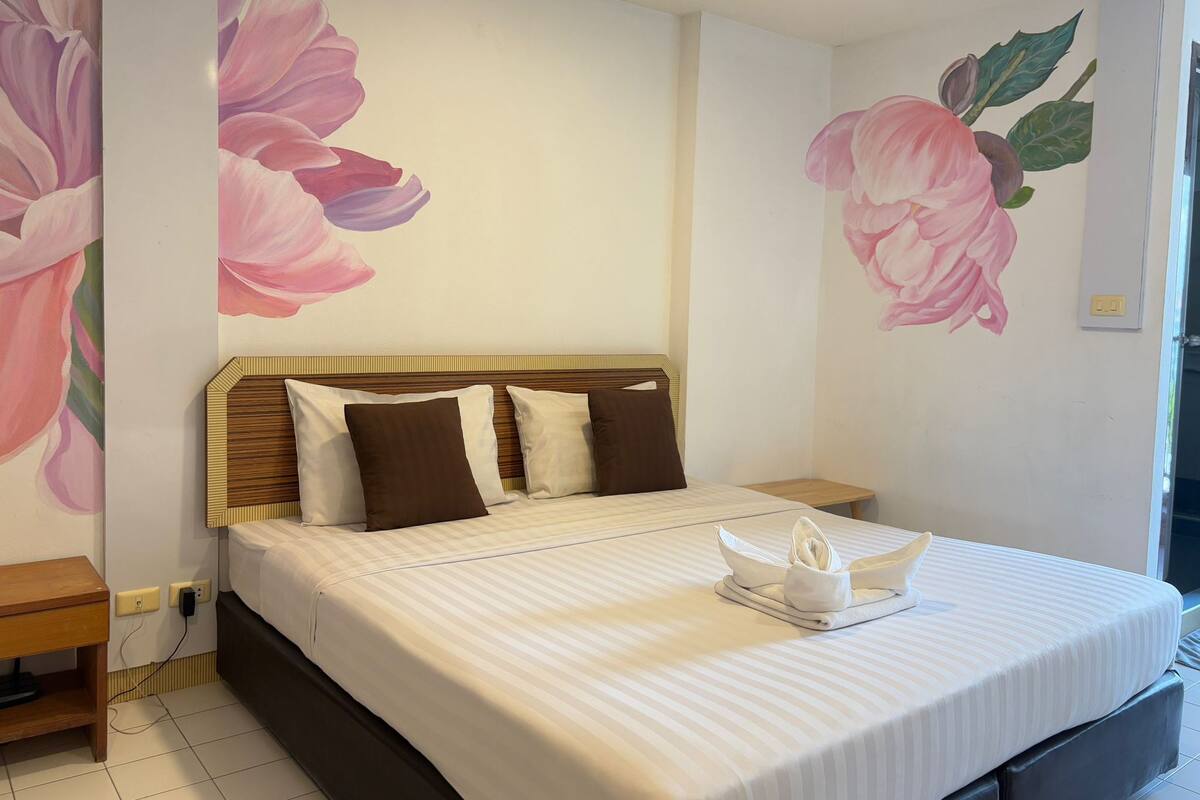 A hotel room with a large bed, a wooden headboard, and floral wall art.