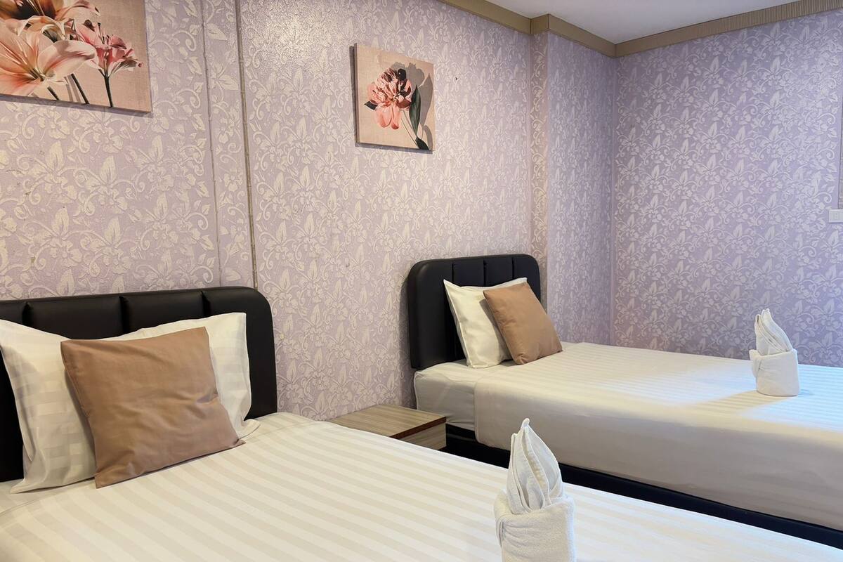 A hotel room with two beds, each with a pillow and a folded towel.