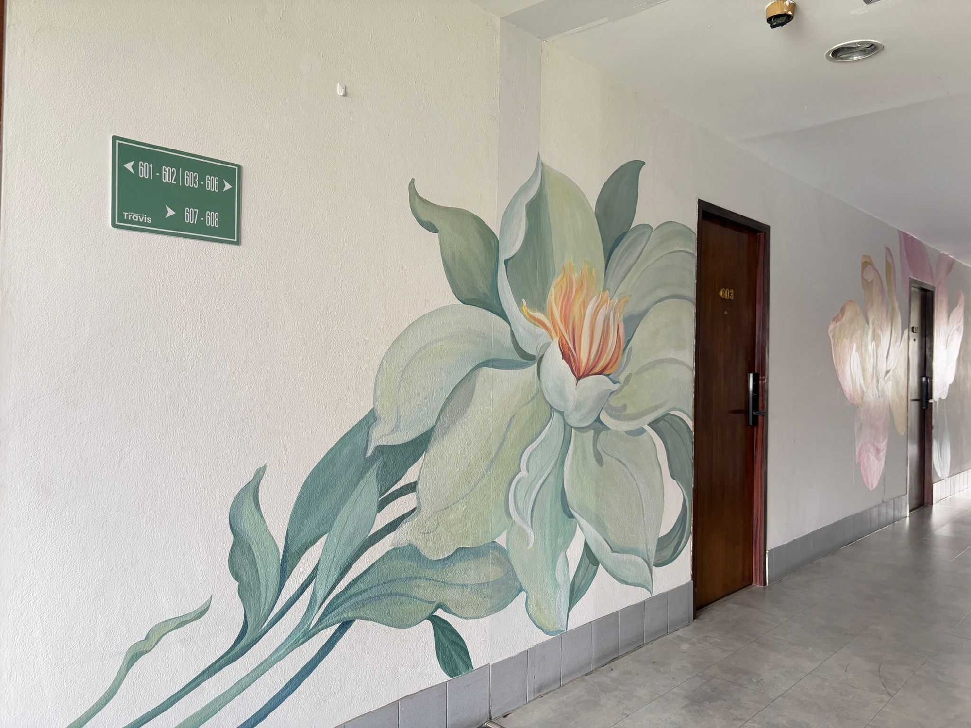 A hallway with directional signs and a floral mural.