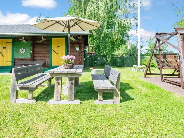 A wooden cabin with a green door, a yellow door, and a picnic table with benches.
