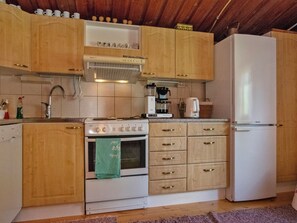 Une cuisine avec des meubles de rangement en bois, une cuisinière, un réfrigérateur et une machine à café.