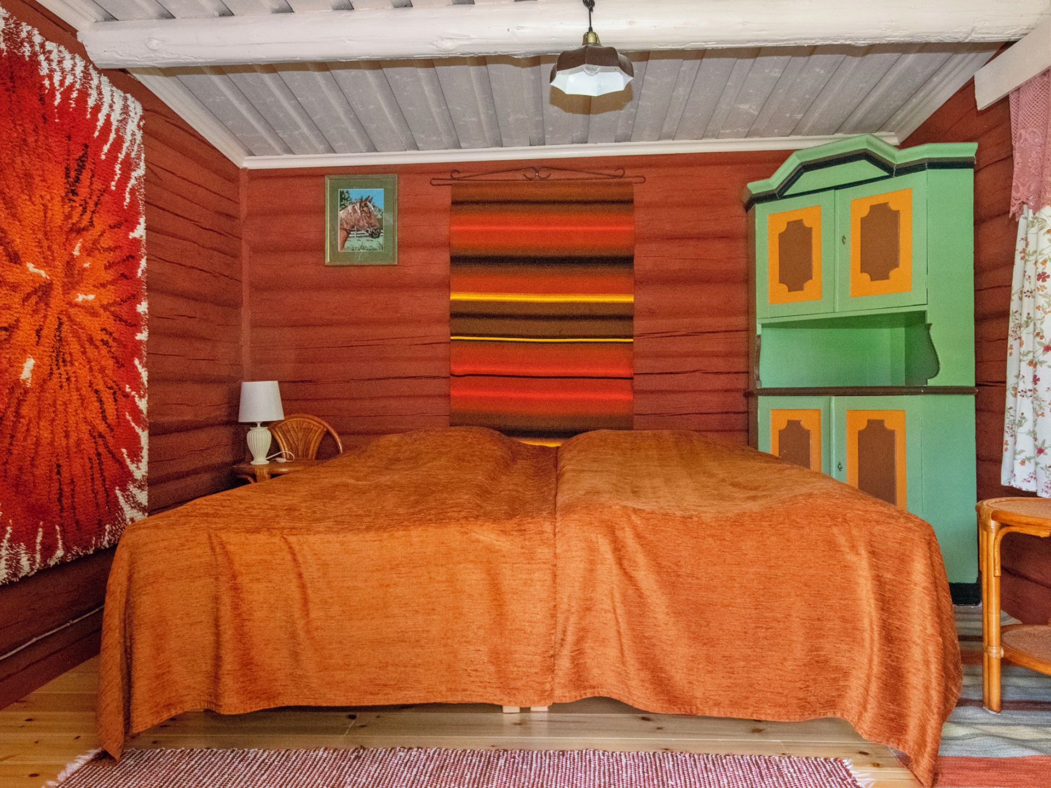 Una habitación con cama, lámpara, un cuadro y un armario verde.