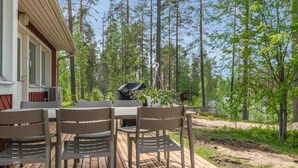 Eine Terrassenausrichtung mit Tisch und Stühlen, umgeben von einem Wald.