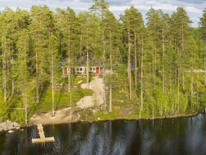 A cabin surrounded by dense forest, a dock extending into a calm lake, and a dirt path leading to the cabin. - Vacation home Malmi by Interhome (Sonkajärvi)