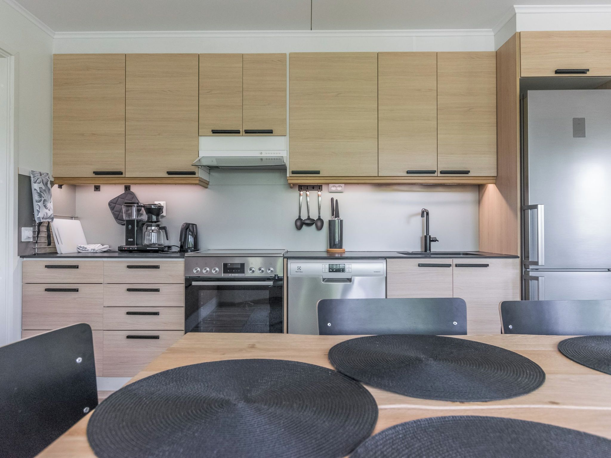 Eine moderne Küche mit Holzausstattung, einem Backofen, einer Spülmaschine und einem Kühlschrank.