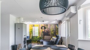 Ein moderner Konferenzraum mit einem großen Tisch, schwarzen Stühlen und einer Waldmalerei an der Wand.