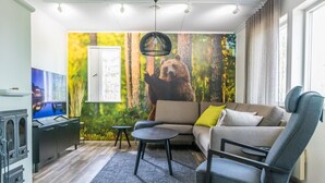Ein modernes Wohnzimmer mit einer großen Bärenmalerei, einer Couch, einem Sessel, einem Fernseher und einem Kamin.