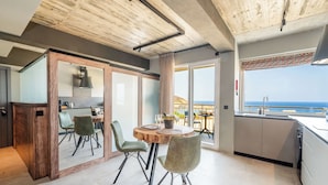 Een moderne keuken met een eethoek, grote ramen en uitzicht op zee.