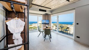 Et moderne værelse med balkon, fjernsyn og spiseplads med stole og bord.