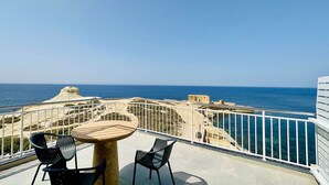 A balcony with a table and chairs overlooking the sea. - Salini Suites Luxury Accommodation with Corner Terrace and Deck Area 501 (Iż-Żebbuġ)