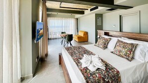 A hotel room with a bed, a TV, a chair, and a view of the outdoors. - Salini Suites Luxury Accommodation with Corner Terrace and Deck Area 501 (Iż-Żebbuġ)