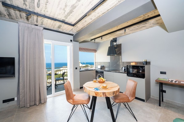 A modern kitchen with a view, a dining area with a round wooden table, and a balcony with a view.