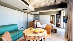 A modern hotel room with a round dining table, a sofa, a bed, and a walk-in closet. - Salini Suites Luxury Accommodation With Terrace and Sea View 101 (Iż-Żebbuġ)