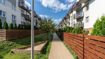 A residential building with multiple balconies, a paved pathway, and a wooden fence.