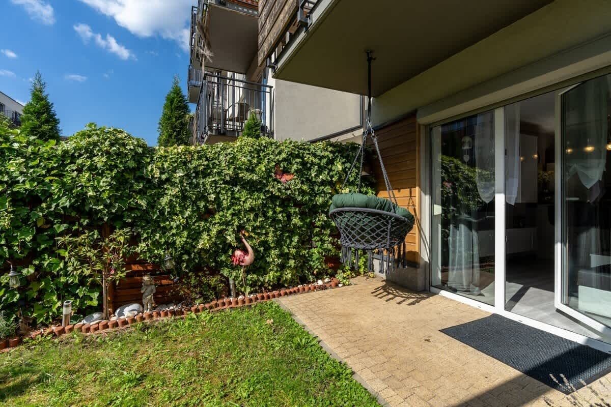 Um bairro residencial com jardim, uma cesta de basquete suspensa e porta de correr de vidro.