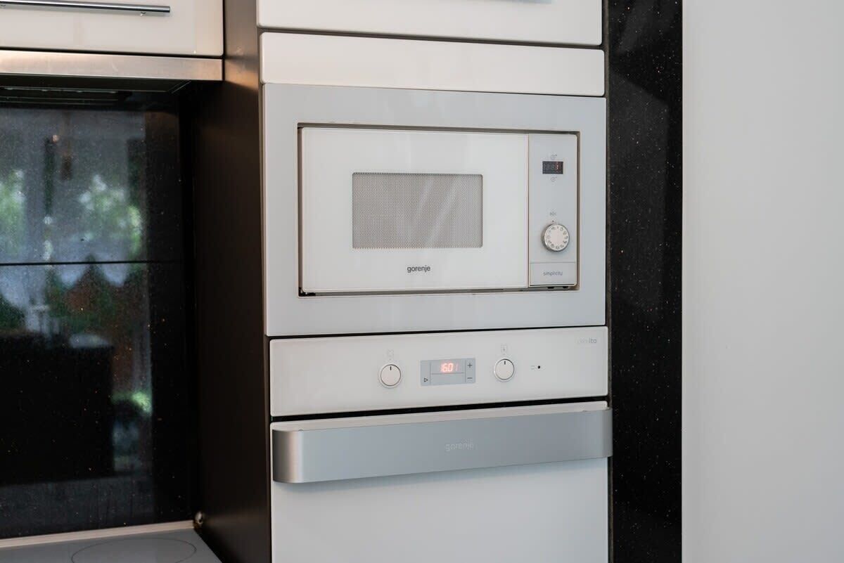 Eine Küche mit integriertem Mikrowellenherd und Backofen, einer digitalen Uhr und einer Bedienkonsole mit Knöpfen.