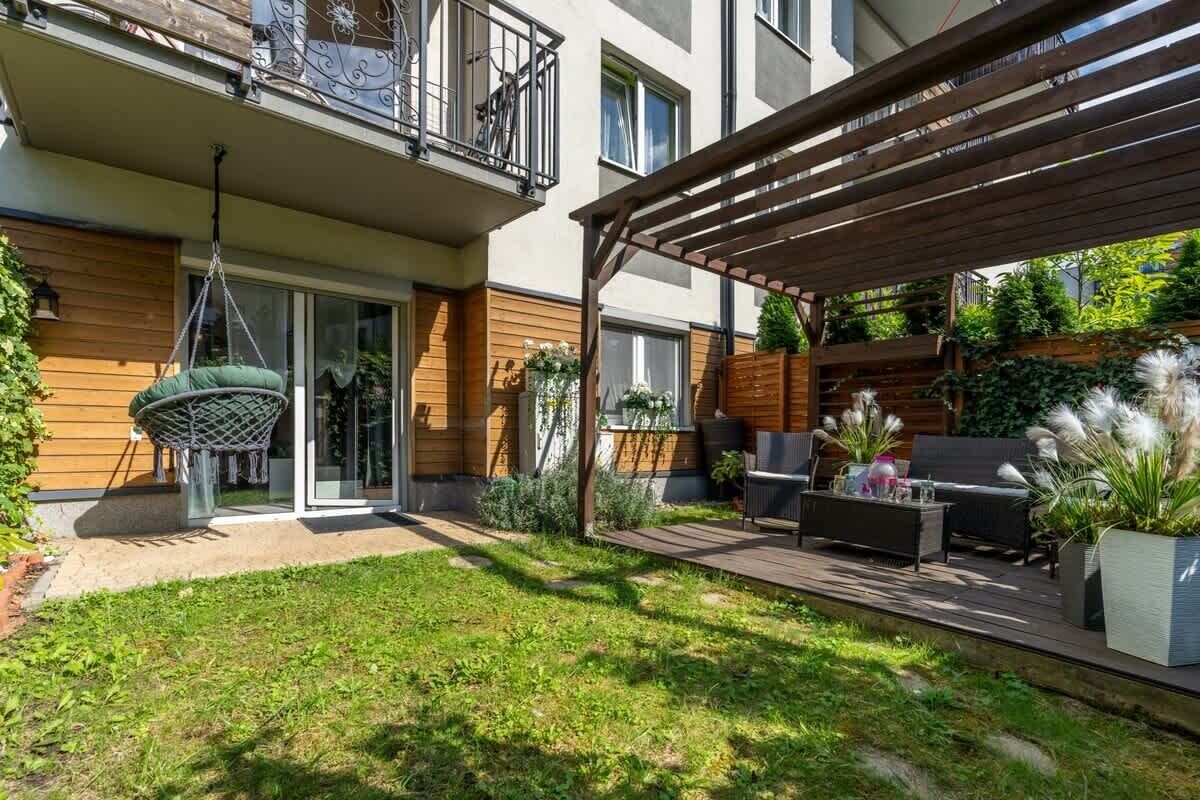 Un apartamento moderno con un patio, mobiliario exterior y una silla colgante.