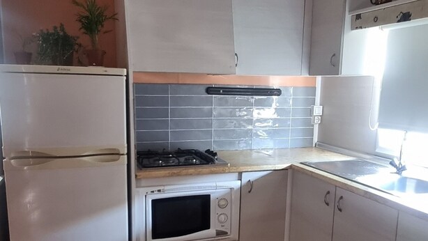 A compact kitchen with a built-in oven, microwave, and sink. - Bungalow con Encanto a 600 Metros de la Playa las 3 Piedras. Aceptamos Mascotas (Chipiona)