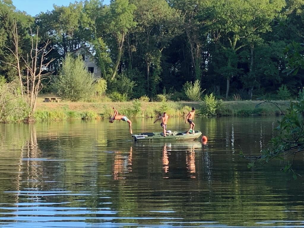 Ein ruhiger See mit einem kleinen Boot, das drei Personen befördert.