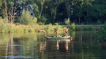 Ein ruhiger See mit einem kleinen Boot, das drei Personen befördert.