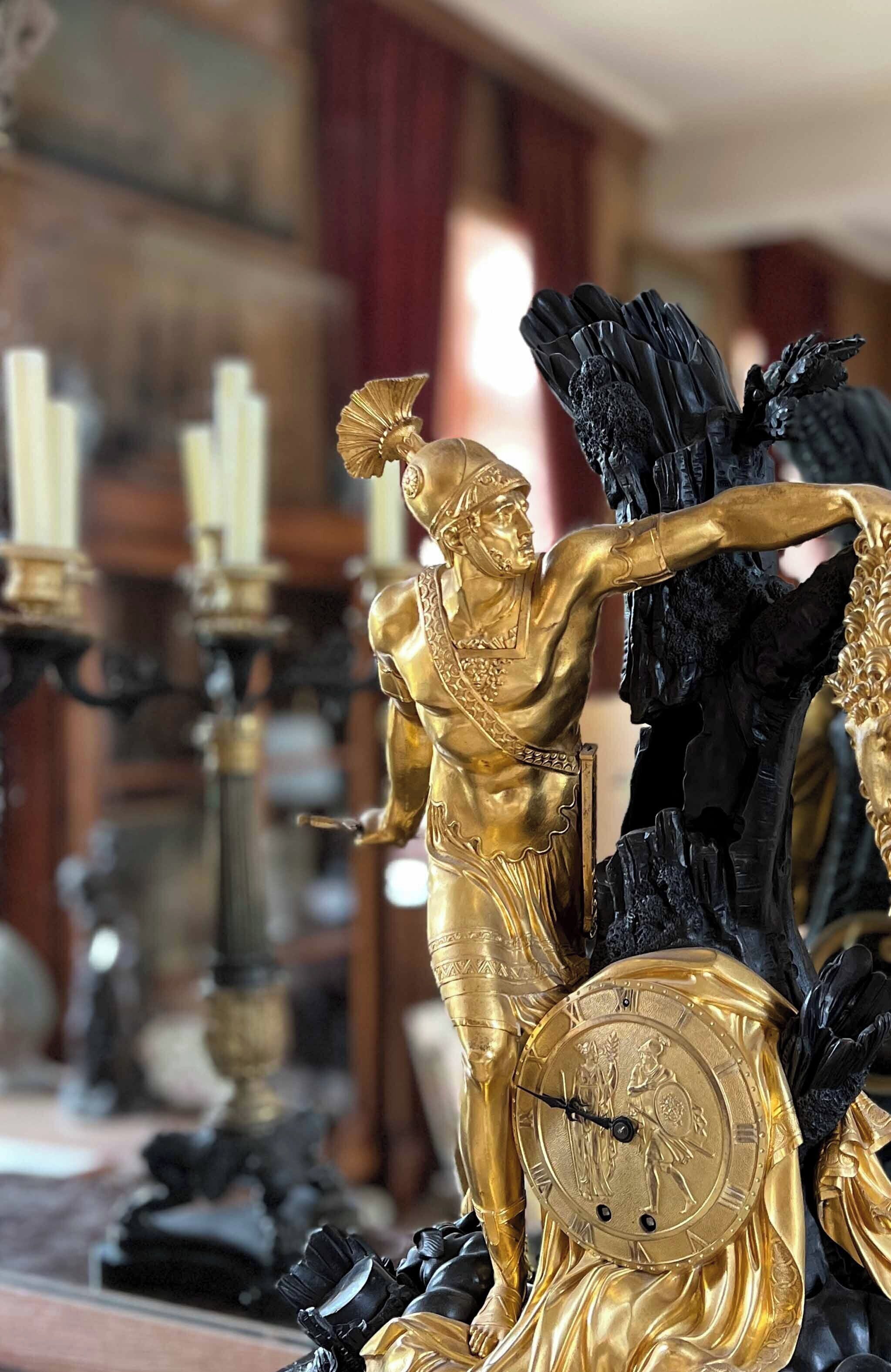 Une statue dorée représentant une figure tenant une horloge, le tout entouré de décorations noires et dorées.