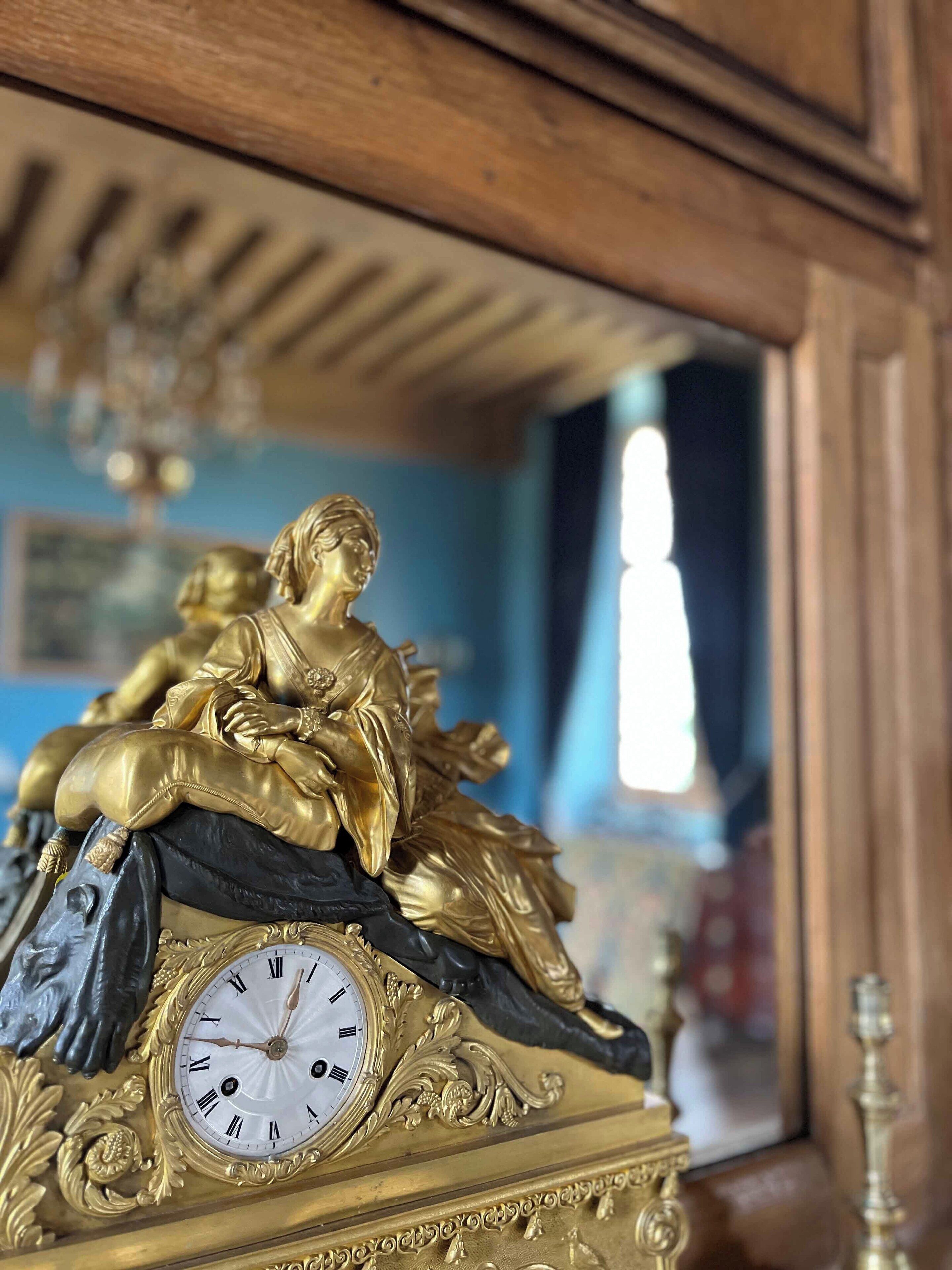 A detailed clock with Roman numerals and a golden statue of a seated figure.