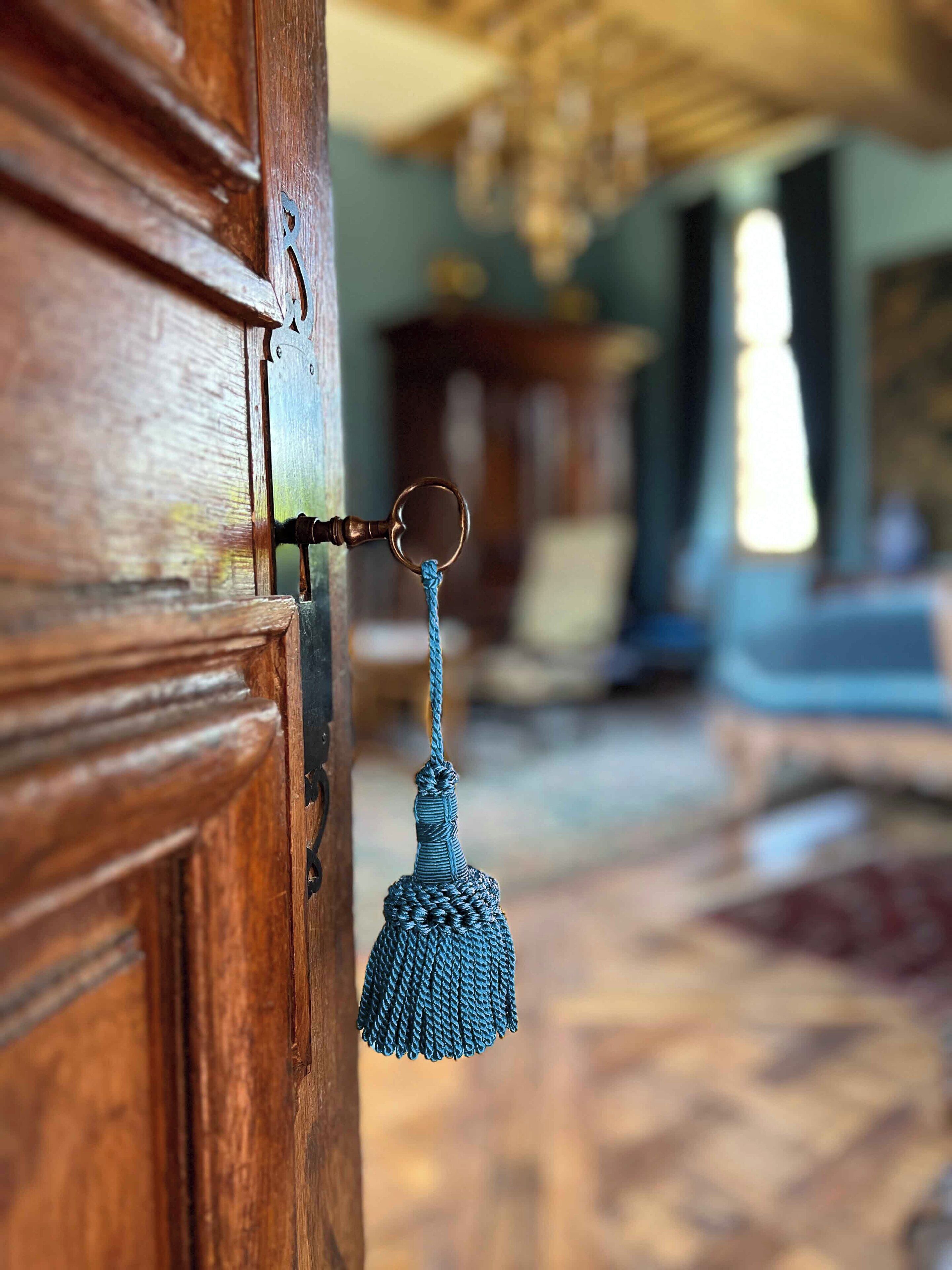 Una puerta de madera con cerradura metálica y un fleco azul colgando.