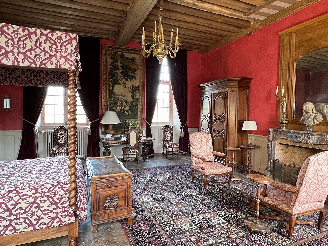 Una habitación tradicional con una cama con dosel, chimenea y muebles clásicos.