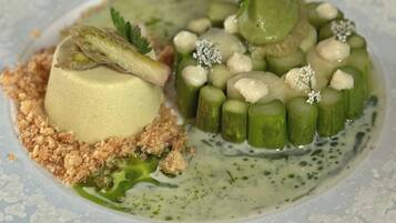 A dessert with a spherical component, green cylindrical pieces, and a crumbly base on a plate.